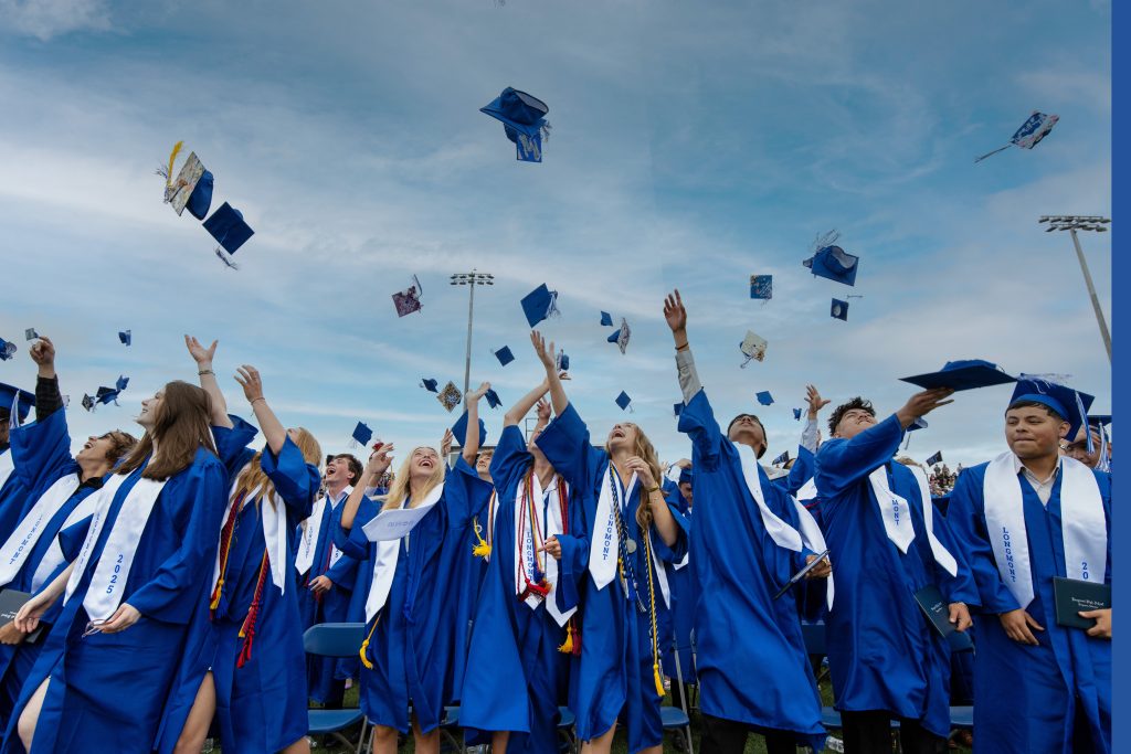 Los graduados, con togas y birretes azules, lanzan alegremente sus birretes al aire durante la ceremonia de graduación.