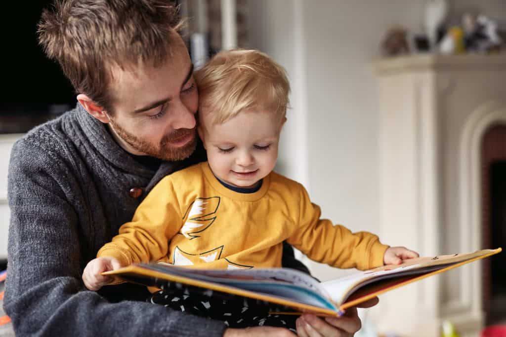Papá e hijo pequeños leyendo juntos