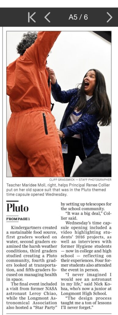 Teacher assists principal in donning a vintage space suit during a themed time capsule event celebrating Pluto.