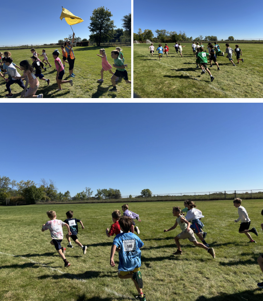 Children running in a field during a race, with a volunteer holding a yellow flag in the background. Clear blue sky.