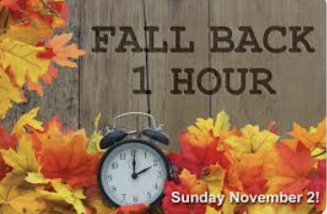 Colorful autumn leaves surround a clock, announcing "Fall Back 1 Hour" for Daylight Saving Time on Sunday, November 2.